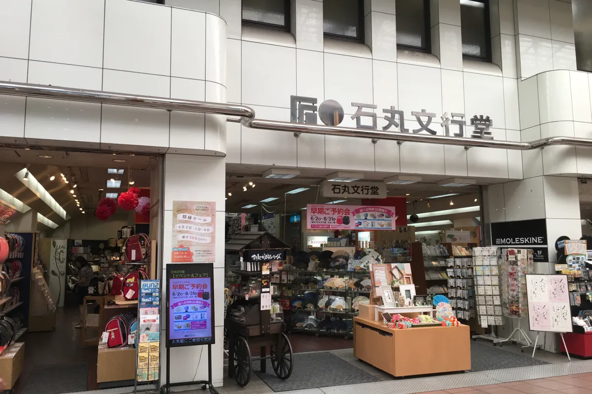 石丸文行堂の店舗の外観（入口の上に「石丸文行堂」の看板と、イベントとフェアの案内）